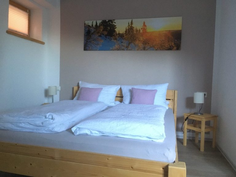 Schlafzimmer Gemütliches Schlafzimmer mit Holzelementen und Baumwollbettwäsche in der Ferienwohnung Neyer in Steibis – Raum zum Durchatmen im Allgäu.